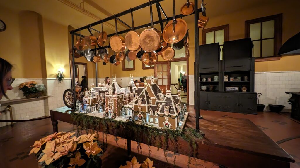 a display of gingerbread houses that look like the Biltmore House and pots from a rack